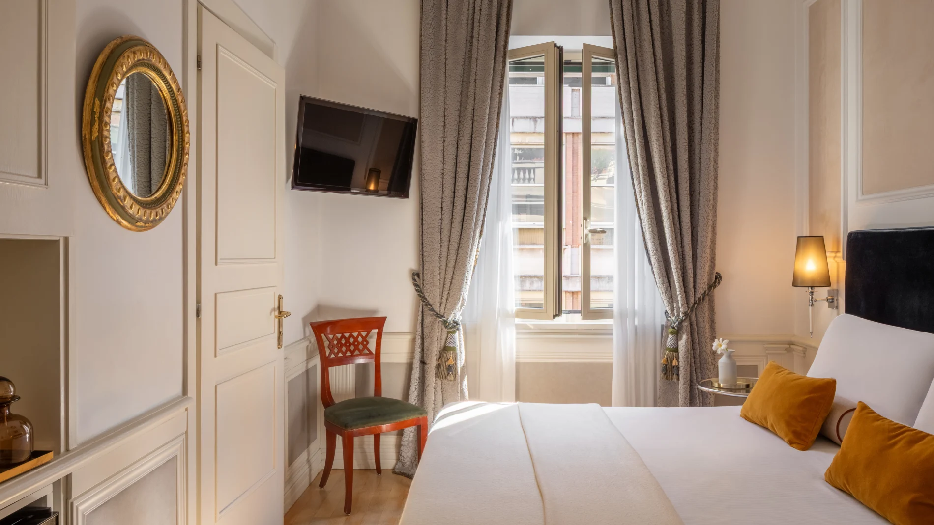 Camera luminosa con letto, finestra aperta, tende damascate, TV e cuscini ocra vicino al Teatro dell'Opera - The Hotel Britannia, BZAR hotels a Roma
