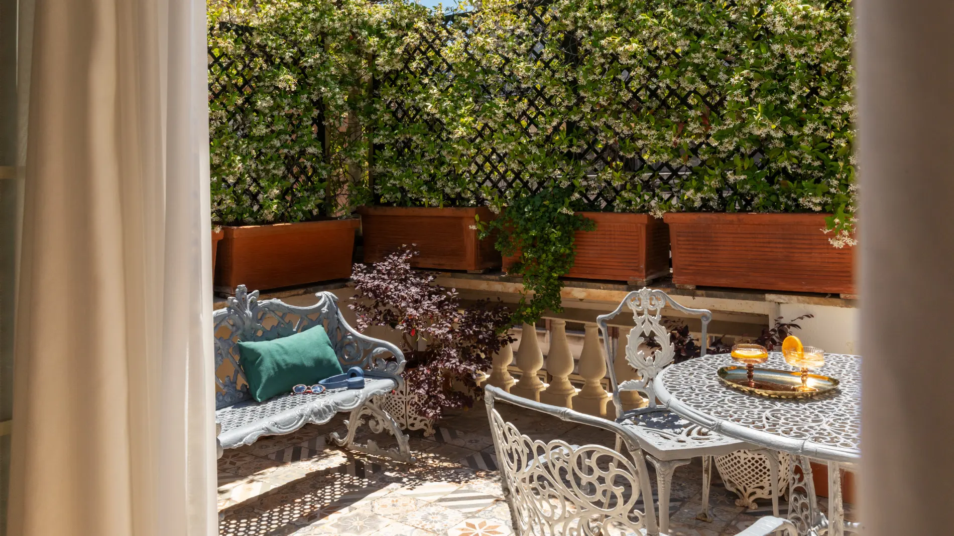 Terrazza privata con tavolo e sedie in ferro battuto, piante fiorite e luce naturale a Roma - The Hotel Britannia, BZAR hotels a Roma