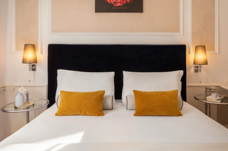 Letto matrimoniale Classic con testiera blu, cuscini ocra e luci da lettura vicino al Teatro dell'Opera - The Hotel Britannia, BZAR hotels a Roma
